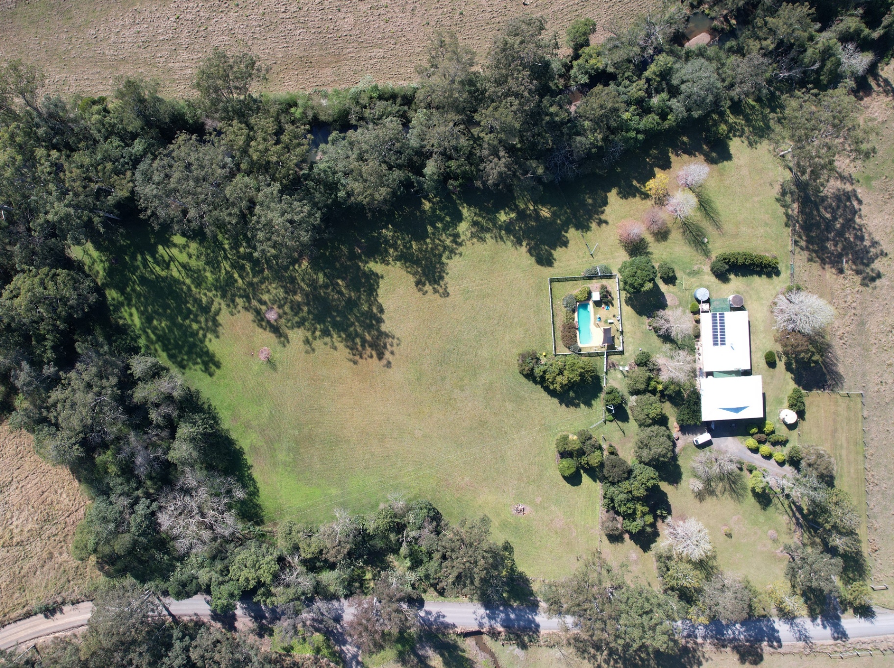 Aerial of open paddock framed by treeline and creek